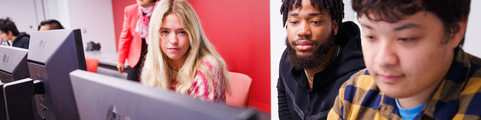 Three students work together at a computer.